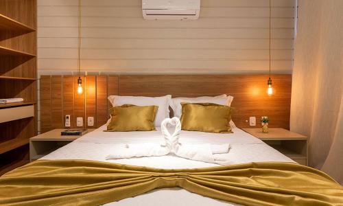 a bedroom with a large white bed with gold pillows at Condado de Urubici in Urubici