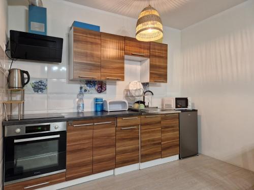 a kitchen with wooden cabinets and a stove at Apartament Komorniki - Osiedla na Skraju Lasu in Komorniki