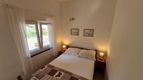 een kleine slaapkamer met een bed en een raam bij Apartmani Ela in Prvić Luka