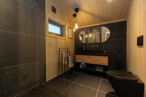 a bathroom with a black toilet and a mirror at High standard cabin in a quiet area in the bossom of nature near Flå in Flå