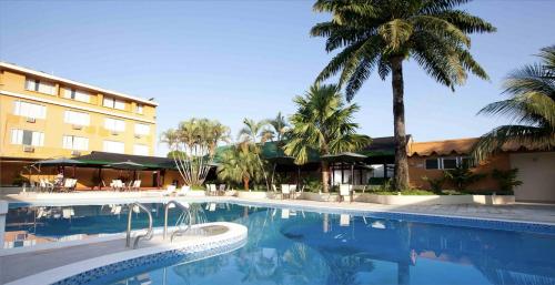 una piscina frente a un hotel con palmeras en Hotel Anaconda, en Leticia