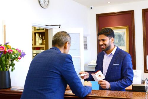 two men in suits shaking hands at a desk at Columba Hotel in Oban