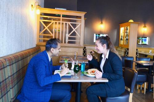 a man and woman sitting at a table in a restaurant at Columba Hotel in Oban