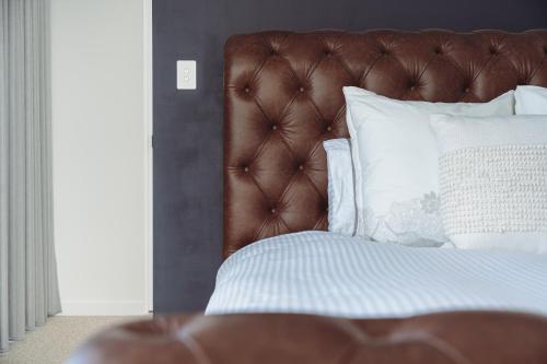 a bed with a brown headboard and white pillows at The Cloud at Sen Vineyard in White Hills