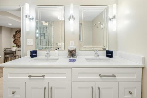 a white bathroom with two sinks and a mirror at Garden Apartment - Decor Upgrades - Capitol Hill in Denver