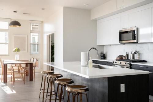 a kitchen with white cabinets and a kitchen island with bar stools at LoHi Clubhouse - Cityscape Panorama - Central LoHi in Denver