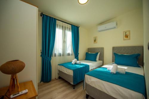1 dormitorio con 2 camas y una ventana con cortinas azules en Villa Star, en Fethiye