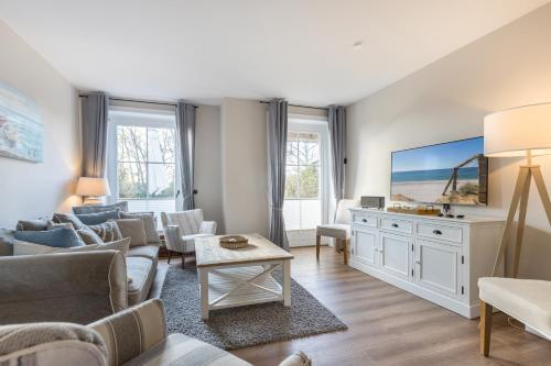 a living room with white furniture and a large screen tv at Ameland App 12 in Wenningstedt