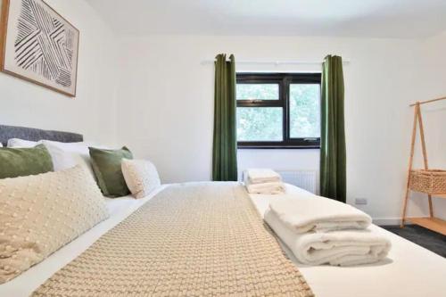 1 dormitorio con cama blanca y cortinas verdes en Eco Home for Large Groups w/ FREE Parking & Wi-Fi, en Bristol