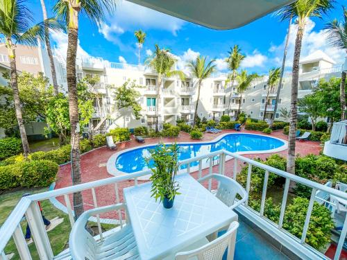uma varanda com uma mesa e cadeiras e uma piscina em TROPICANA Sol CARIBBE del Mar STUDIOS & SUITES PUNTA CANA - playa BAVARO BEACH CLUB & SPA em Punta Cana