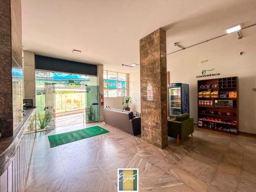 a lobby of a store with a green couch and a drink at Hotel Oscar Econômico Montes Claros in Montes Claros