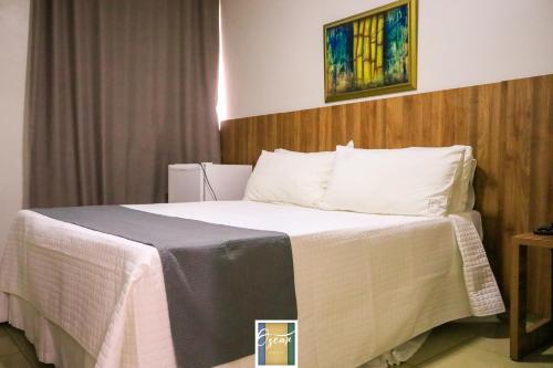 a hotel room with a bed with white sheets at Hotel Oscar Econômico Montes Claros in Montes Claros