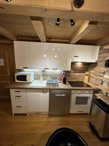 une cuisine avec des armoires blanches, un évier et une cuisinière dans l'établissement Le Wood Megève, à Megève