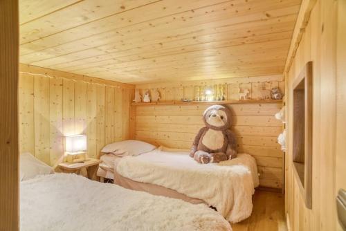 - un ours en peluche assis sur un lit dans une pièce dans l'établissement Le Wood Megève, à Megève