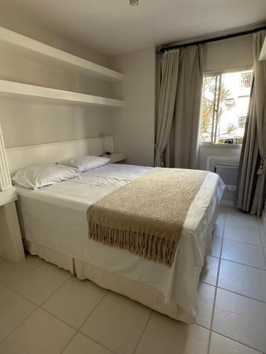 uma cama branca num quarto com uma janela em Apê na Gávea no Rio de Janeiro