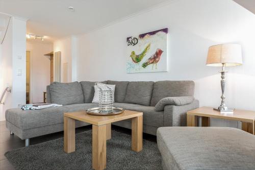 ein Wohnzimmer mit einem grauen Sofa und 2 Tischen in der Unterkunft Oceanhouse, Cordi, App. 9 in Wenningstedt-Braderup