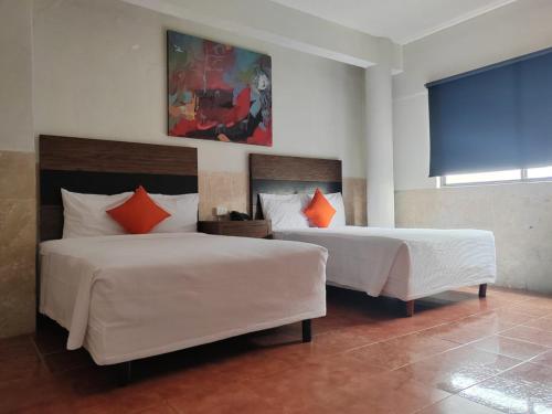 Habitación de hotel con 2 camas con almohadas de color naranja en Bed Bed Hotel Abasolo en Torreón
