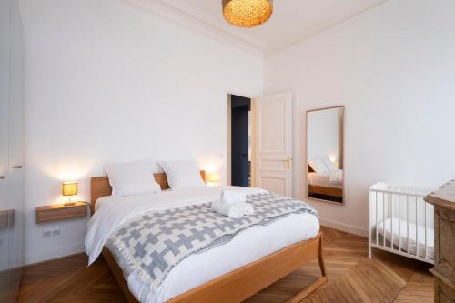 une chambre blanche avec un lit et un miroir dans l'établissement Le Joli Coeur, à Nancy