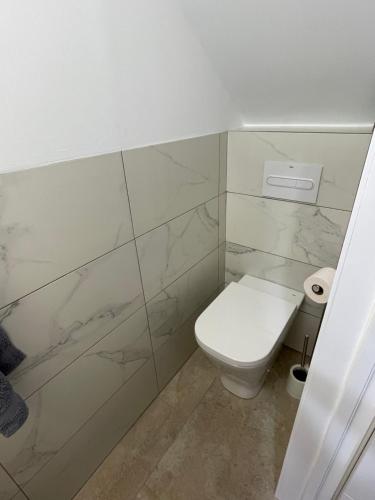 a bathroom with a white toilet and marble walls at Las Americas Bungamar apartment in Playa de las Americas