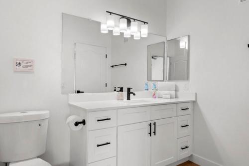 ein weißes Badezimmer mit einem Waschbecken und einem Spiegel in der Unterkunft TWO Bright CozySuites Apartment Downtown Chandler 06 & 07 in Chandler