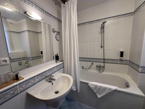 La salle de bains est pourvue d'un lavabo, d'une baignoire et d'un miroir. dans l'établissement Hotel U Zámečku Cihelny, à Karlovy Vary