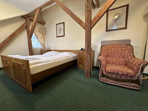 - une chambre avec un lit et une chaise dans l'établissement Hotel U Zámečku Cihelny, à Karlovy Vary