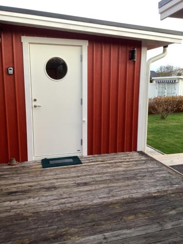 białe drzwi na czerwonym budynku z drewnianym tarasem w obiekcie Skönaste stället som finns. Bara 300 m till havet. w mieście Lysekil