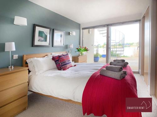 ein Schlafzimmer mit einem großen Bett mit einer roten Decke in der Unterkunft Clearwater - Lower Mill in Somerford Keynes
