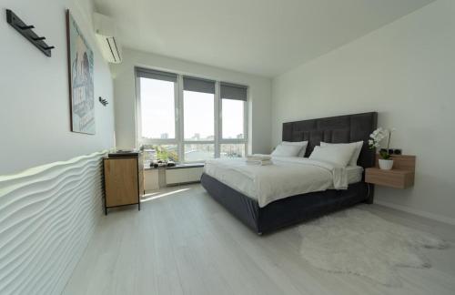 a bedroom with a large bed and a large window at Солнечные просторные апартаменты Метро Минская in Kyiv