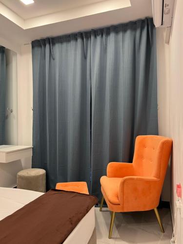 an orange chair sits next to a bed in a room at Green Star City Apartment in Dehiwala