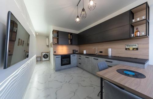 a kitchen with black cabinets and a wooden table at Солнечные просторные апартаменты Метро Минская in Kyiv