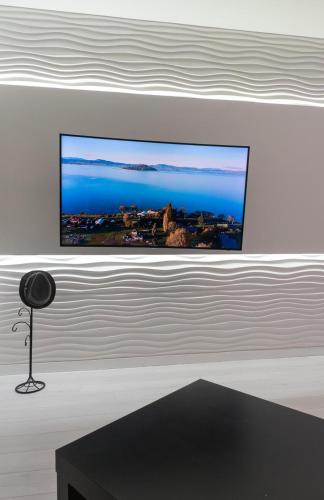 a flat screen tv on a wall above a table at Солнечные просторные апартаменты Метро Минская in Kyiv