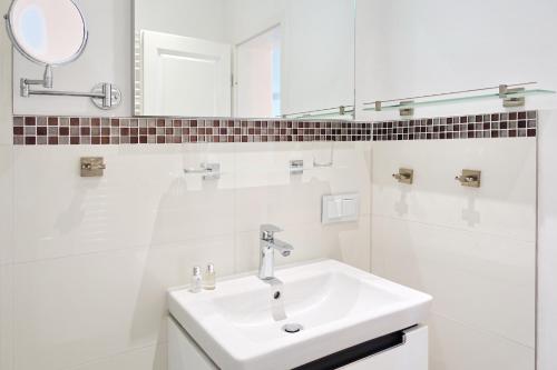 ein weißes Badezimmer mit Waschbecken und Spiegel in der Unterkunft Sylter Stubn  in Westerland