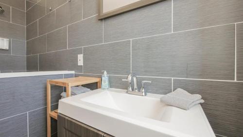 La salle de bains est pourvue d'un lavabo blanc et de carrelage gris. dans l'établissement Atlantic Suite by the Boardwalk 3A, à Atlantic City