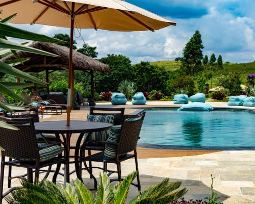 a table and chairs with an umbrella next to a pool at Espaço Vento Solar in São Roque