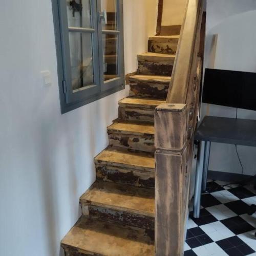 una antigua escalera de madera en una habitación con ventana en Maison en charpentes - 2 nuits minimum, en Lyons-la-Forêt