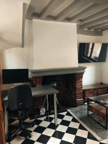 escritorio y silla en una habitación con chimenea en Maison en charpentes - 2 nuits minimum, en Lyons-la-Forêt