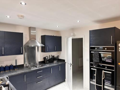 a kitchen with black cabinets and a stove top oven at Stylish Lux in Morley
