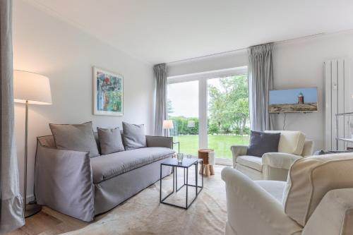 uma sala de estar com um sofá e uma mesa em Dorfteichblick App 5 em Wenningstedt