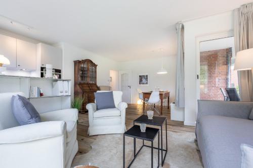uma sala de estar com duas cadeiras brancas e uma mesa em Dorfteichblick App 5 em Wenningstedt