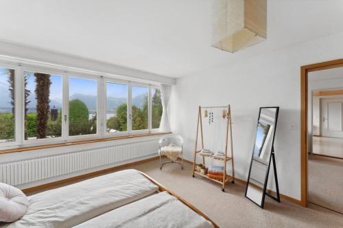 1 dormitorio con cama, ventana y espejo en Lakeview apartment in beautiful Oberhofen en Oberhofen am Thunersee