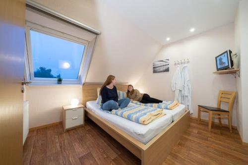2 persone sedute su un letto in una stanza di Ferienwohnung Kiebitz IV a Otterndorf