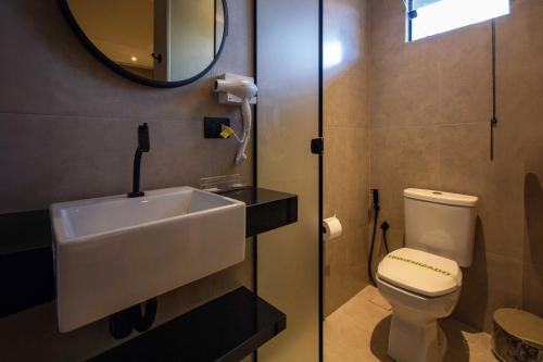 a bathroom with a sink and a toilet and a mirror at Oasis Motel in Piracicaba