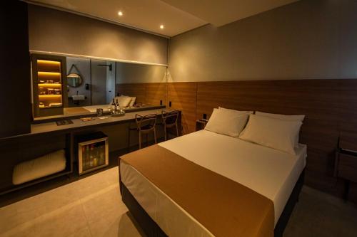 a bedroom with a bed and a bathroom with a sink at Oasis Motel in Piracicaba
