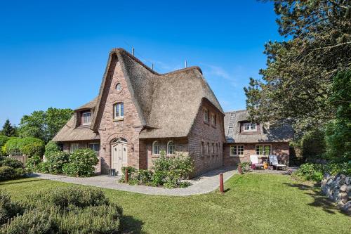 a large brick house with a thatched roof at Familier Hygge Hus in Braderup