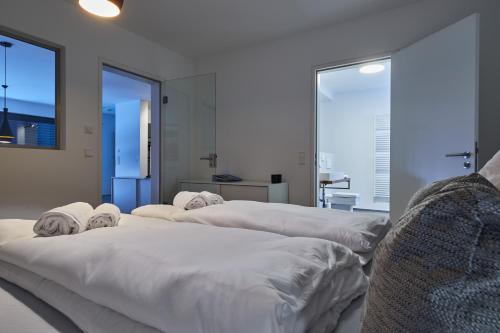three white beds in a room with large windows at Cosmopolitan in Überlingen