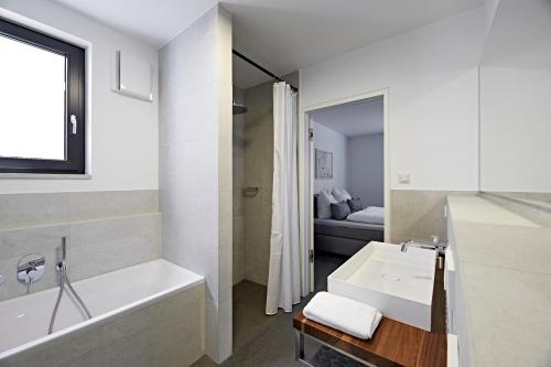 een witte badkamer met een bad en een wastafel bij Cosmopolitan in Überlingen