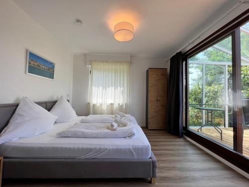 ein Schlafzimmer mit einem Bett und einem großen Fenster in der Unterkunft Ferienhaus Wellnesshütte mit Außenwhirlpool und herrlichem See-und Alpenblick in Überlingen