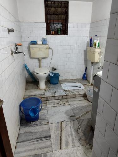 a dirty bathroom with a toilet and two buckets at Ashiyana in Bhubaneshwar