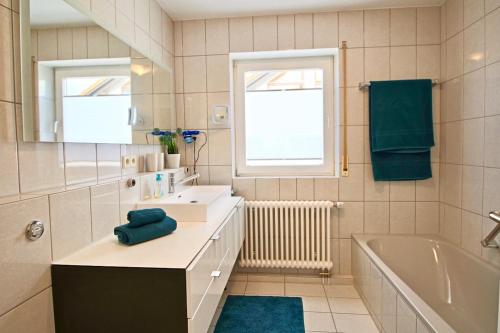 a bathroom with a sink and a tub and a mirror at Maisonette Alpenblick in Überlingen